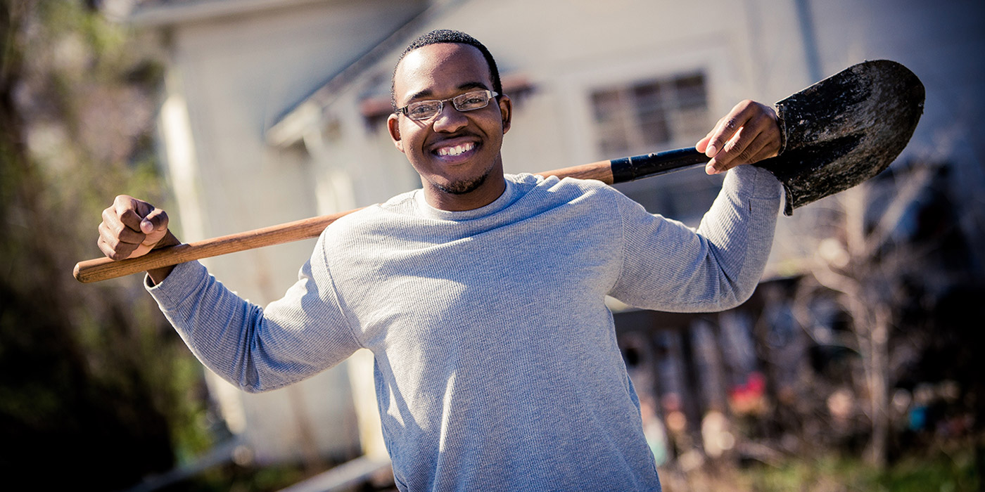 Student holding a shovel as part of a community project