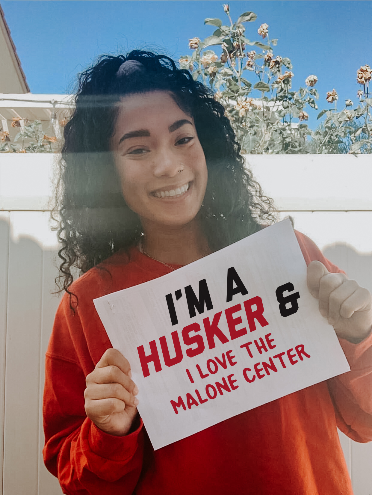 Kami holding a sign that says "I'm a Husker and I love the Malone Center."