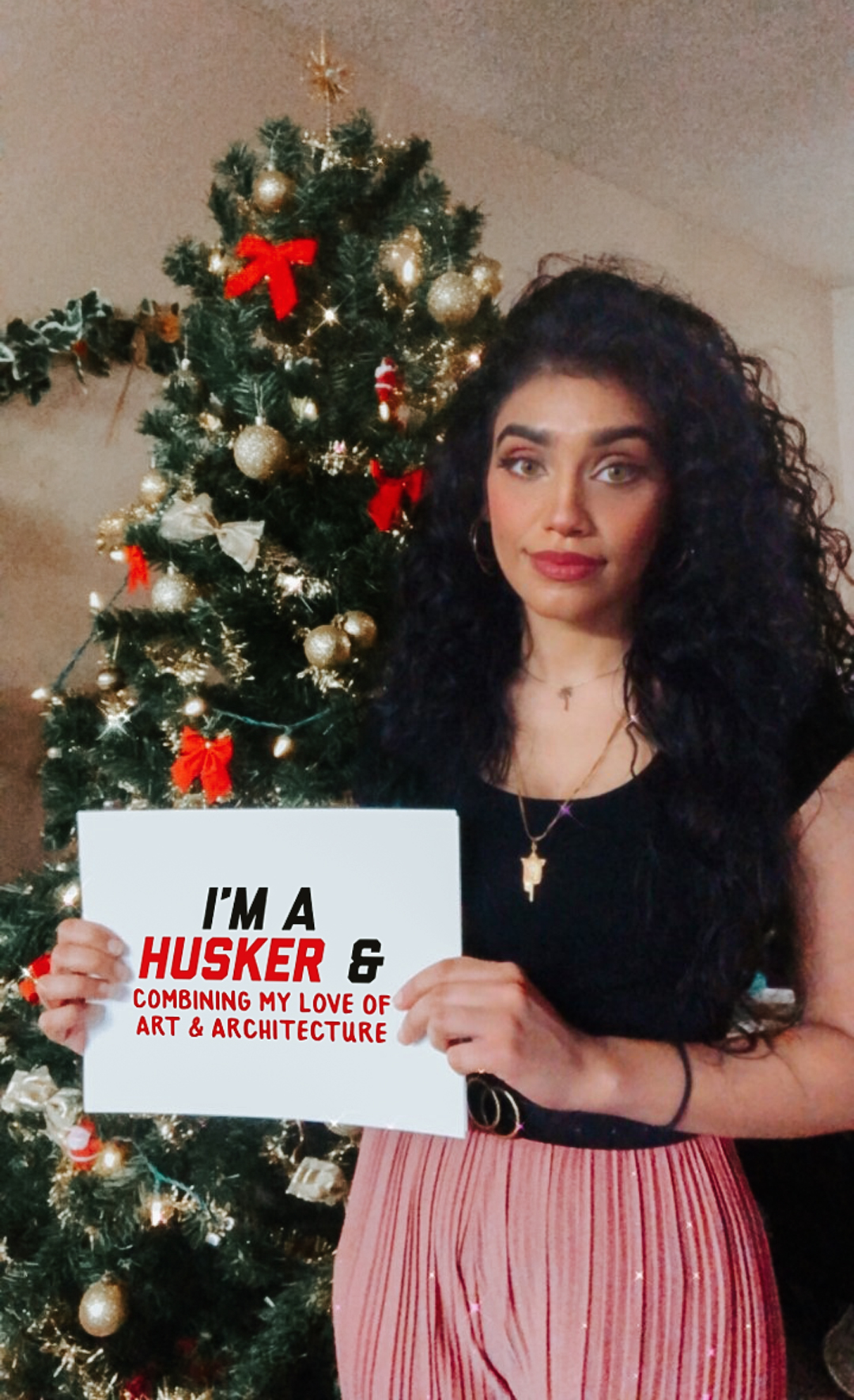 Samah holding a sign that says "I'm a Husker and combining my love of art and architecture."