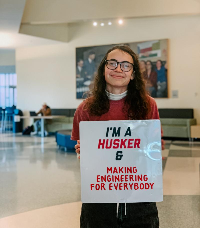 Dorian smiles for a photo holding a sign that says "I'm a Husker & making engineering for everybody"